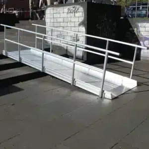 Stabile Aluminium-Rampe für barrierefreien Zugang, platziert auf einer Treppe mit Geländer und strukturierten Oberflächen.