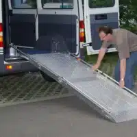 Rampe für den Zugang zu einem Kleintransporter, genutzt von einer Person, die auf die Rampe geht. Der Transporter steht offen im Hintergrund.