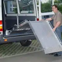 Person bedient eine mobile Rampe an einem Transporter, um den Zugang zu erleichtern.