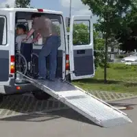 Transporter mit Rampe, die verwendet wird, um eine Person im Rollstuhl einzuladen. Ein Mann schiebt den Rollstuhl in den Transporte.