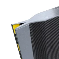 Nahaufnahme der gummierten Auflage einer schwarzen, texturierten Rollstuhlrampe mit gelben und schwarzen Details.