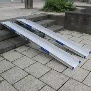 Aluminium-Rampen für barrierefreien Zugang, angebracht an einer Treppe aus Steinplatten.