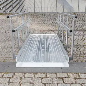 Eine Rollstuhlrampe aus Metall mit Handläufen auf beiden Seiten