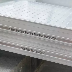 Nahaufnahme einer Rollstuhlrampen-Oberfläche mit einer perforierten Struktur und Reihen von kreisförmigen Löchern entlang des Randes.