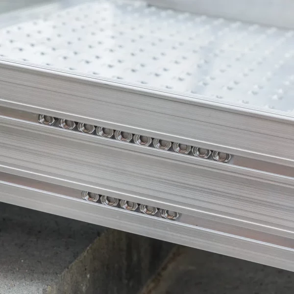 Nahaufnahme einer Rollstuhlrampen-Oberfläche mit einer perforierten Struktur und Reihen von kreisförmigen Löchern entlang des Randes.