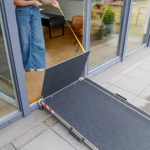 Eine Person hält ein gelbes Zugband neben eine tragbare Rampe