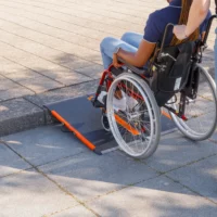 Eine Person im Rollstuhl benutzt eine tragbare Rampe