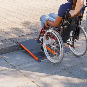 Eine Person im Rollstuhl benutzt eine tragbare Rampe