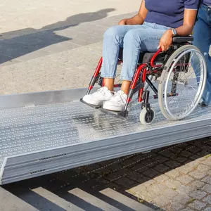Eine Frau schiebt eine Person im Rollstuhl eine feste Rollstuhlrampe hinauf