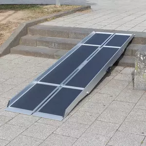 Eine tragbare Rollstuhlrampe ist auf einem gefliesten Gehweg über die Außenstufen gelegt.