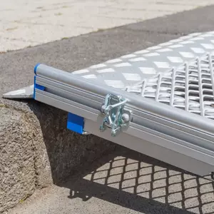 Eine Rollstuhlrampe aus Aluminium mit einer Klemme ist auf einer Treppenstufe angebracht.
