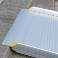 Nahaufnahme des oberen Auflagewinkels einer tragbaren Aluminium-Rollstuhlrampe auf einer Betonstufen