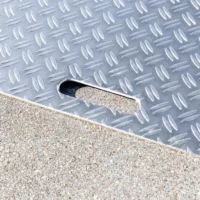 Nahaufnahme einer Rollstuhlrampe aus Aluminium mit einem erhabenen Rautenmuster als Rutschsicherung und einem ovalen Ausschnitt als Handgriff