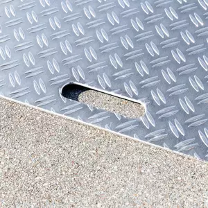 Nahaufnahme einer Rollstuhlrampe aus Aluminium mit einem erhabenen Rautenmuster als Rutschsicherung und einem ovalen Ausschnitt als Handgriff