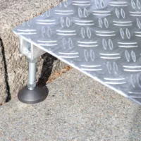 Nahaufnahme des verstellbaren Fußes einer Alumnium Rollstuhlrampe zur Überbrückung einer einzelnen Stufe.