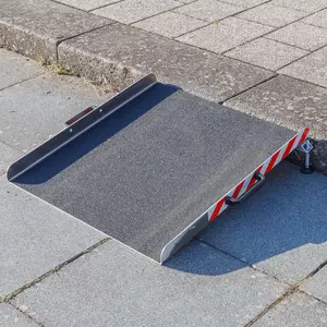 Eine tragbare Rollstuhlrampe aus Alumnium steht vor einer einzelnen Stufe