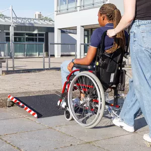 Eine Person im Rollstuhl wird von einer anderen Person zu einer mobile Rollstuhlrampe