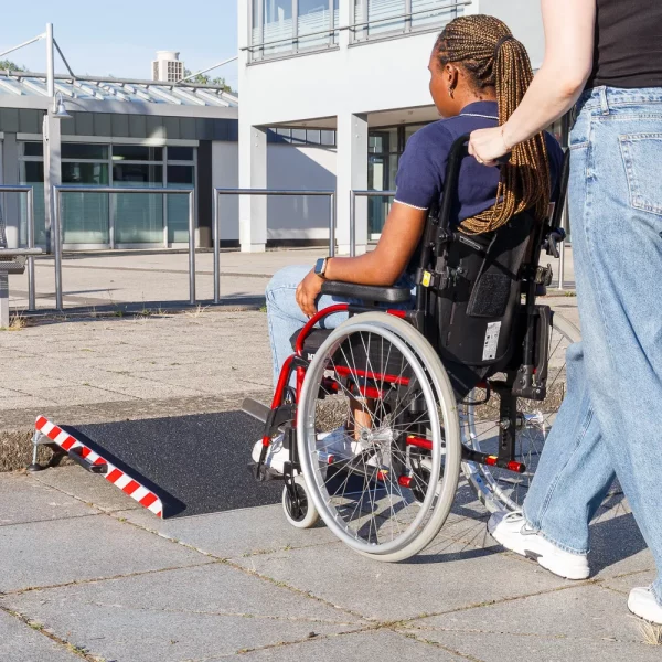 Eine Person im Rollstuhl wird von einer anderen Person zu einer mobile Rollstuhlrampe