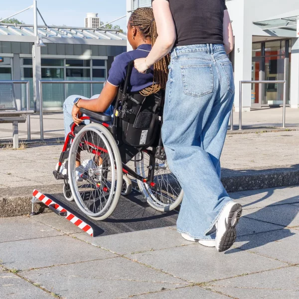 Eine Person im Rollstuhl wird von einer anderen Person unterstützt