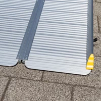 Nahaufnahme des unteren Endes einer tragbaren Aluminium-Rollstuhlrampe mit einer gelben Sicherheitskante