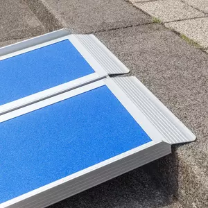 Nahaufnahme des oberen Auflagewinkels einer blauen und klappbaren Rollstuhlrampe aus Aluminium auf der Vorderkante einer Treppenstufe aufliegend.