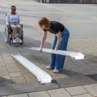 Eine Frau baut eine tragbare Rollstuhlrarmpe aus Aluminium auf