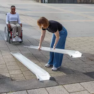 Eine Frau baut eine tragbare Rollstuhlrarmpe aus Aluminium auf