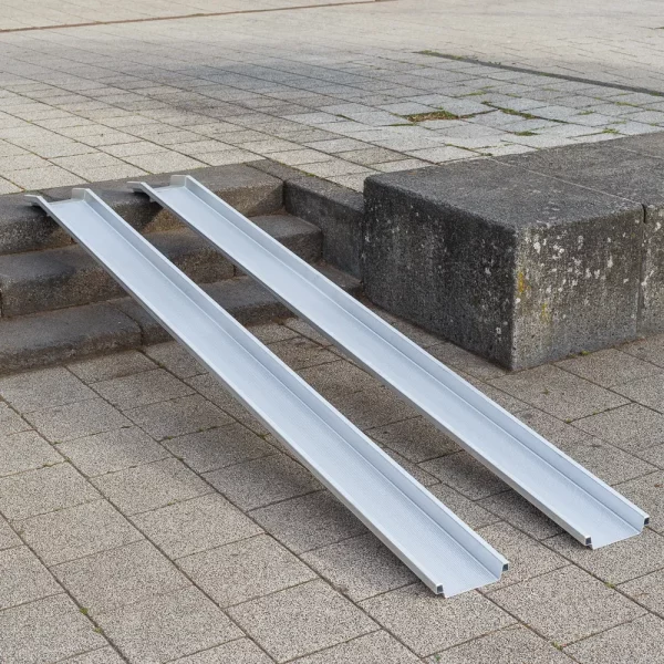21 Rollstuhlrampe leicht diagonal links Zwei Schienen einer Rollstuhlrampe aus Aluminium ist über einer Betontreppe im Außenbereich platziert.