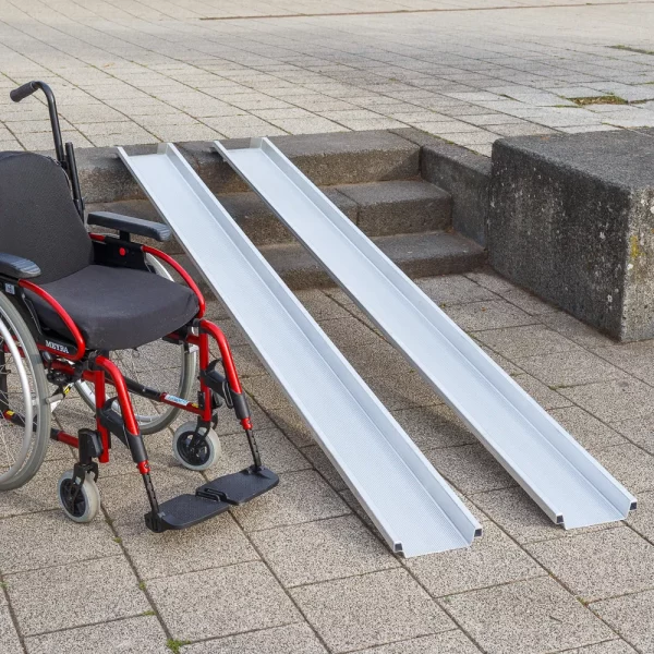 Ein roter Rollstuhl steht links neben zwei Schienen einer Rollstuhlrampe