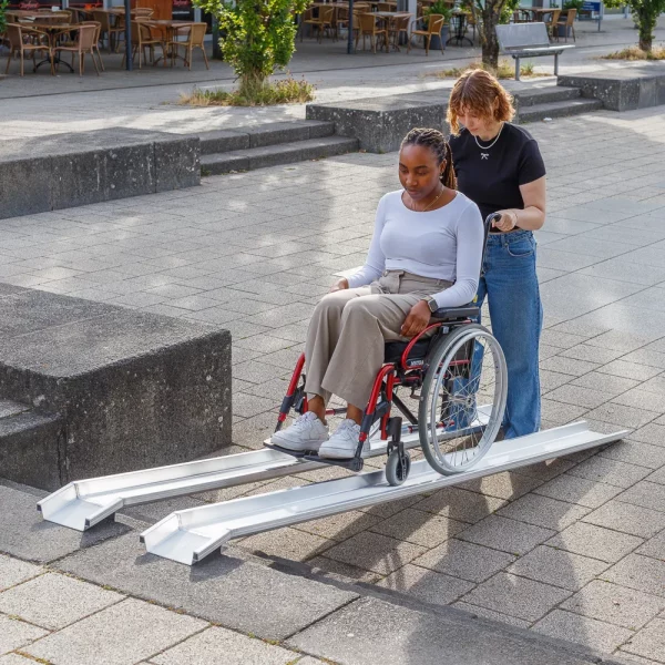 Eine Frau im roten Rollstuhl auf einer tragbaren Schienenrampe aus Aluminium