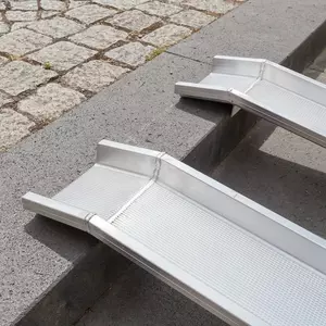 Detailaufnahme der Aufliegefläche von zwei parallel ausgerichteten Schienen einer Schienenrampe auf der obersten Stufe einer Treppe im Außenbereich.