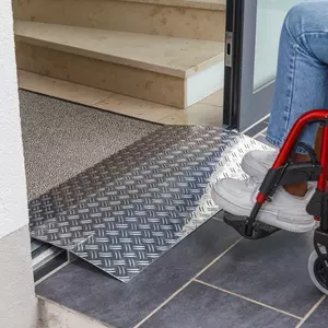 Eine Person im Rollstuhl nähert sich einer Schwellenbrücke