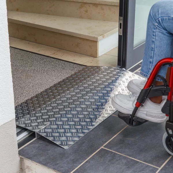 Eine Person im Rollstuhl nähert sich einer Schwellenbrücke