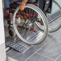 Eine Person im Rollstuhl fährt über eine Schwellenbrücke