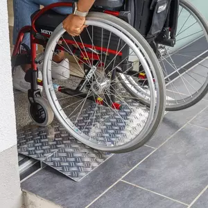 Eine Person im Rollstuhl fährt über eine Schwellenbrücke