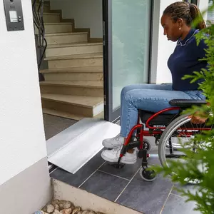 Eine Frau im Rollstuhl benutzt eine Schwellenbrücke