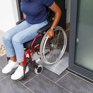 Eine Person im Rollstuhl benutzt eine Schwellenbrücke