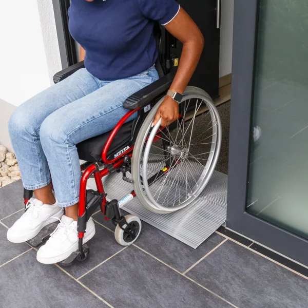 Eine Person im Rollstuhl benutzt eine Schwellenbrücke