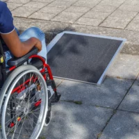 Eine Person im Rollstuhl nähert sich einer tragbaren Rampe