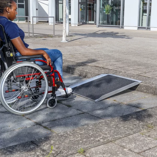 Eine Person im Rollstuhl nähert sich einer tragbaren Rampe