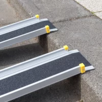 Detailaufnahme der oberen Auflage einer zweiteiligen Aluminiumrampe mit schwarzer rutschsicherer Fahrfläche und gelben Endkappen