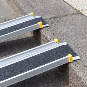 Detailaufnahme der oberen Auflage einer zweiteiligen Aluminiumrampe mit schwarzer rutschsicherer Fahrfläche und gelben Endkappen