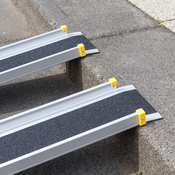 Detailaufnahme der oberen Auflage einer zweiteiligen Aluminiumrampe mit schwarzer rutschsicherer Fahrfläche und gelben Endkappen