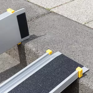 Detailaufnahme der oberen Auflage und der Gummierung einer zweiteiligen Rollstuhlrampe aus Aluminium mit gelben Schutzkappen