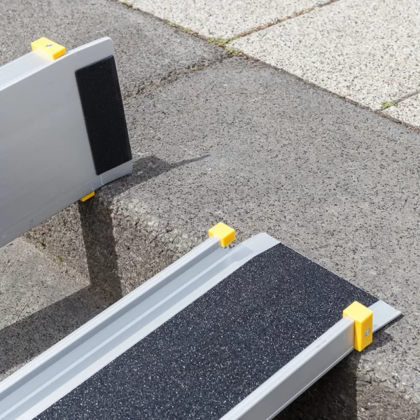 Detailaufnahme der oberen Auflage und der Gummierung einer zweiteiligen Rollstuhlrampe aus Aluminium mit gelben Schutzkappen