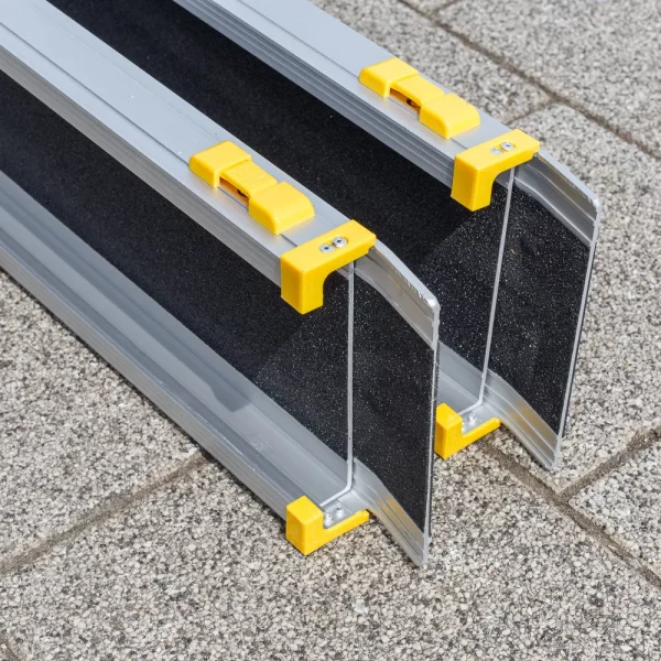 Eine zweiteilige Rollstuhlrampe mit schwarzer Oberfläche und gelben Kunststoffenden