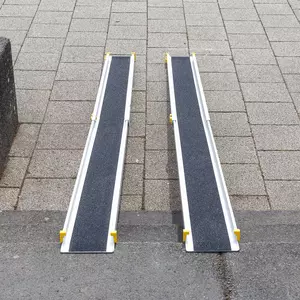 Zwei tragbare Rollstuhlrampen aus Aluminium mit rutschfester schwarzer Oberfläche sind auf einer Treppe platziert und verbinden zwei Ebenen miteinander.