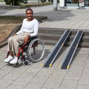 Eine Frau im Rollstuhl sitzt neben tragbaren Rollstuhlrampen