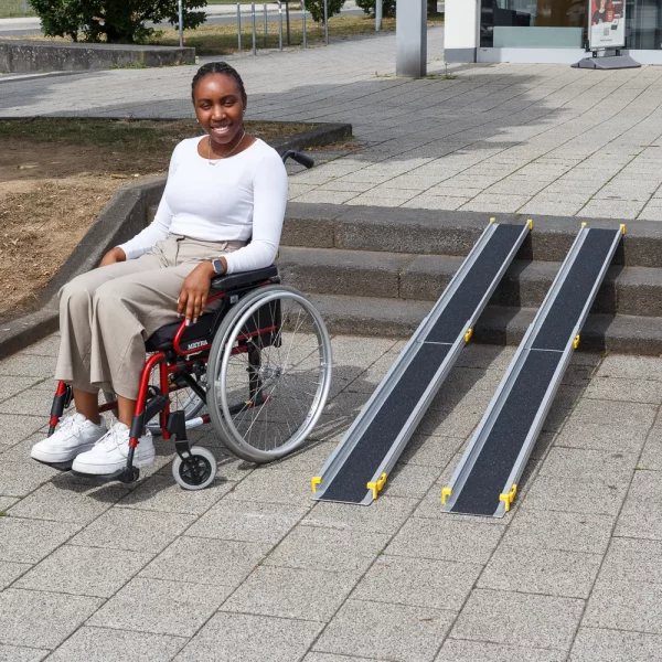 Eine Frau im Rollstuhl sitzt neben tragbaren Rollstuhlrampen