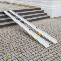 Zwei tragbare Rollstuhlrampen über Steinstufen auf einem kopfsteingepflasterten Platz
